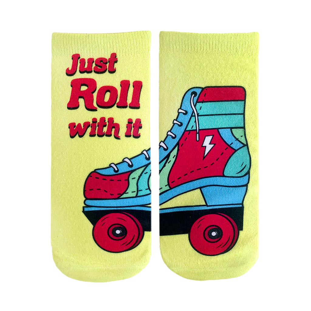 Pair of pastel yellow ankle socks. One sock shows text 'Just Roll With It', the other features a retro-style roller skate graphic with red, blue, and teal accents. [lf]