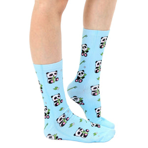 A pair of light blue socks with a pattern of cartoon pandas eating bamboo.