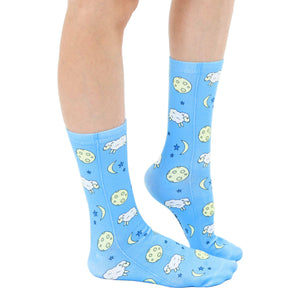 A pair of blue socks with a pattern of white sheep, yellow moons, and stars.
