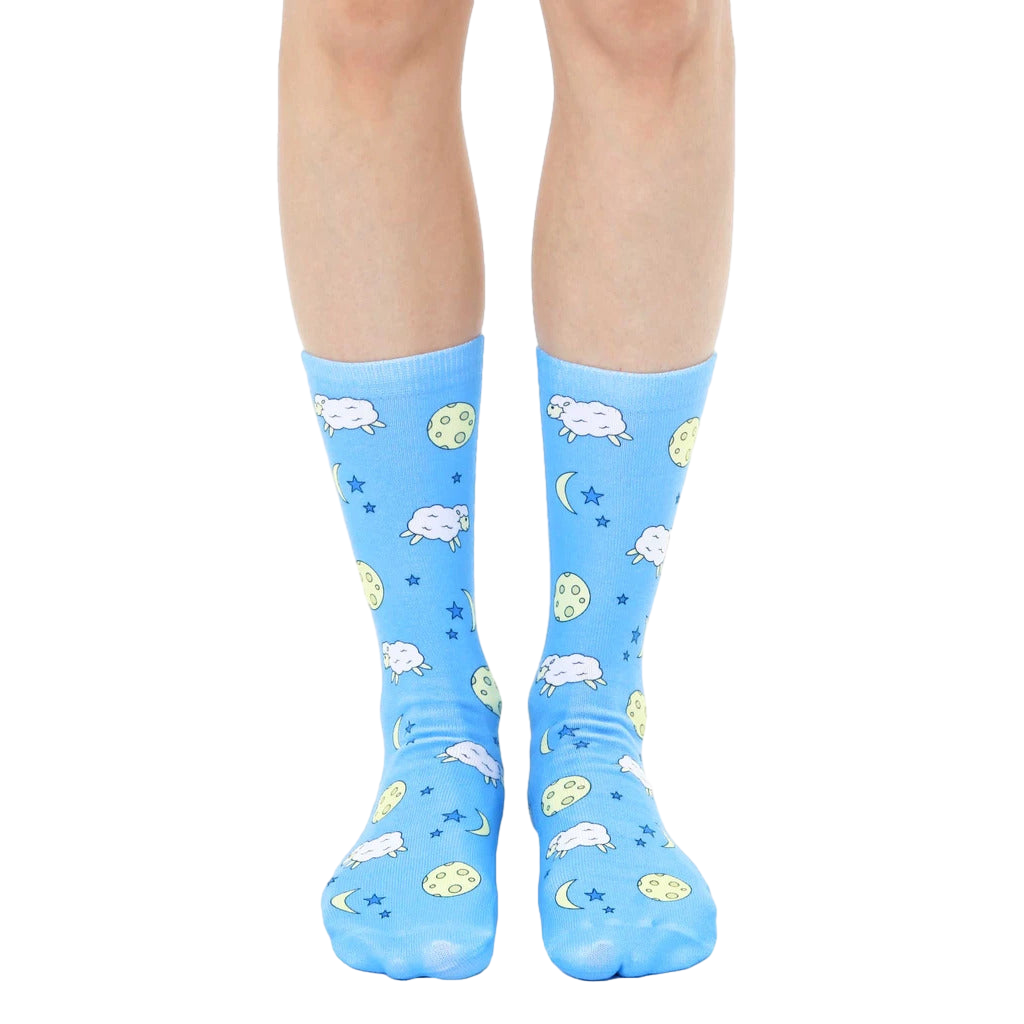 Pair of light blue crew socks with a whimsical design featuring cartoon sheep, moons, and stars. [lf]