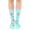 A pair of light blue crew socks with a fun design. Sloths lounging on pink inner tubes in a pool are repeated against a tropical background with yellow stars, moons, and leaves. [lf]