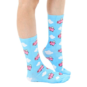 A pair of blue socks with a pattern of cartoon pigs with wings flying through clouds.