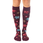Pair of women's burgundy knee-high socks with colorful elephant and sun designs. [lf]