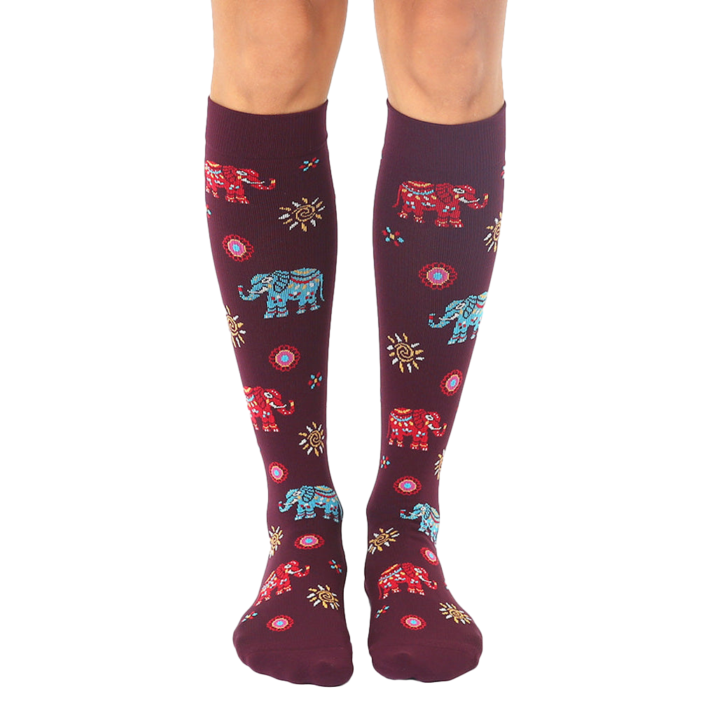 Pair of women's burgundy knee-high socks with colorful elephant and sun designs. [lf]