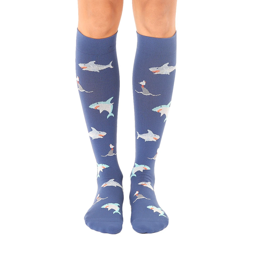 Pair of blue knee-high socks with a repeating pattern of cartoon sharks. Sharks are in teal, white, and orange. [lf]