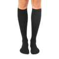 Solid black knee-high socks worn on a person's legs against a dark background, showing a smooth knit texture.