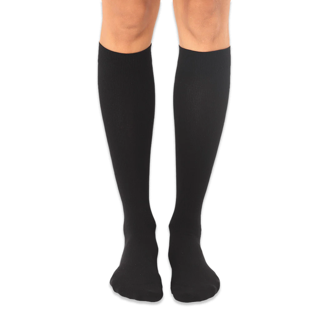 Solid black knee-high socks worn on a person's legs against a dark background, showing a smooth knit texture.