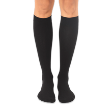 Solid black knee-high socks worn on a person's legs against a dark background, showing a smooth knit texture.