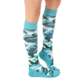 Lifestyle shot: Woman's legs wearing teal knee-high camo socks. [lf]
