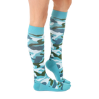 Lifestyle shot: Woman's legs wearing teal knee-high camo socks. [lf]