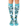 Pair of teal knee-high socks with a green, white, and blue camouflage pattern.  The socks have a teal cuff. [lf]