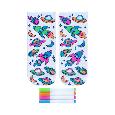 Pair of white ankle socks featuring a colorful space-themed design of rockets, planets, and UFOs.  Includes four fabric markers.