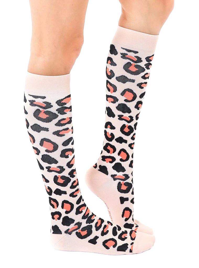 Lifestyle shot showing a woman's legs wearing the coral and black leopard print knee-high socks. [lf]