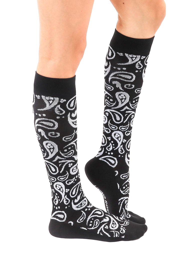 Lifestyle shot of a person wearing the black and silver paisley knee-high socks. [lf]