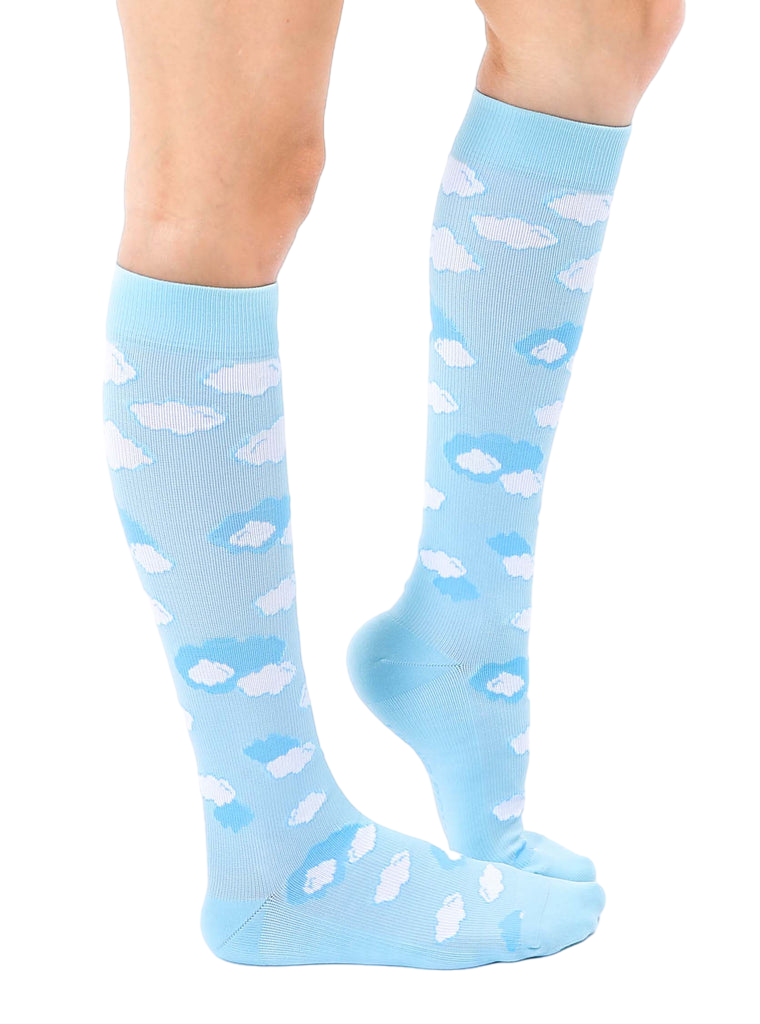 Lifestyle shot of a person's leg wearing a light blue knee-high sock with a white cloud print. The sock is slightly angled, showcasing the design. [lf]
