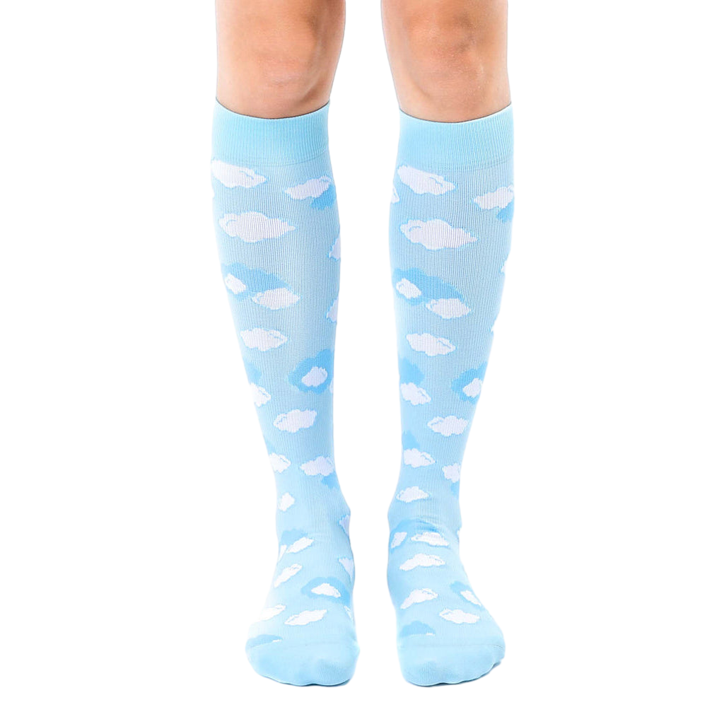 Pair of light blue knee-high socks with a scattered white cloud pattern. Shown on a model's legs against a white background. [lf]
