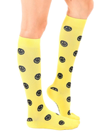 Lifestyle shot showing yellow smiley face knee-high socks on a model's legs. [lf]
