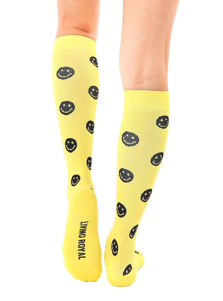 Close-up of the back of the yellow smiley face knee-high socks, showcasing the 'Living Royal' logo. [lf]