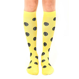 women's knee-high yellow socks with a cheerful black smiley face pattern. perfect for expressing your sunny disposition.  