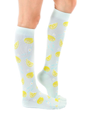 Lifestyle shot of a person wearing the lemon knee-high socks, showing the socks from the side. [lf]