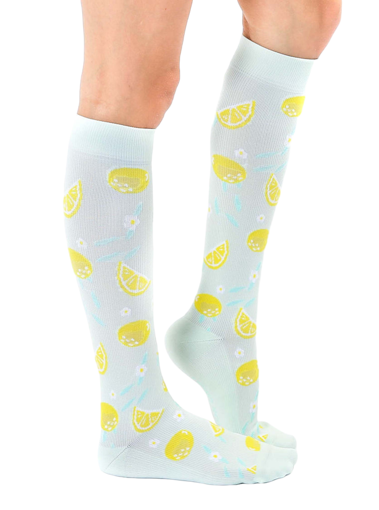 Lifestyle shot of a person wearing the lemon knee-high socks, showing the socks from the side. [lf]