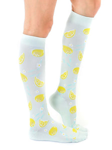 A pair of light blue knee-high socks with a pattern of lemons and white flowers.