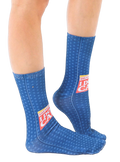 Lifestyle shot showing the 'Breaking News: I Don't Care' socks on a person's feet, showcasing the fit and design on a leg. [lf]