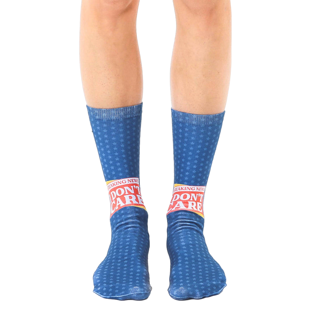 A pair of blue crew socks with a repeating star pattern and a bold 'Breaking News: I Don't Care' graphic in red and yellow. [lf]