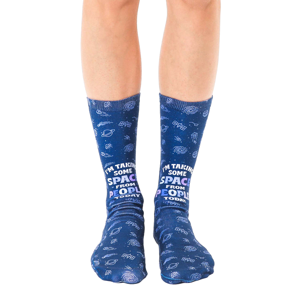 Pair of navy blue crew socks with a whimsical space-themed design, planets, shooting stars, and the text 'I'm taking some space from people today'. [lf]