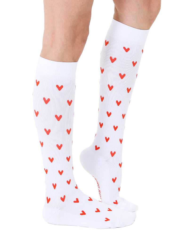 Lifestyle shot of a person's legs wearing the white knee-high socks with red hearts. [lf]