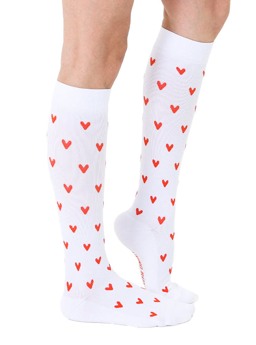 A pair of white knee-high socks with a pattern of red hearts.