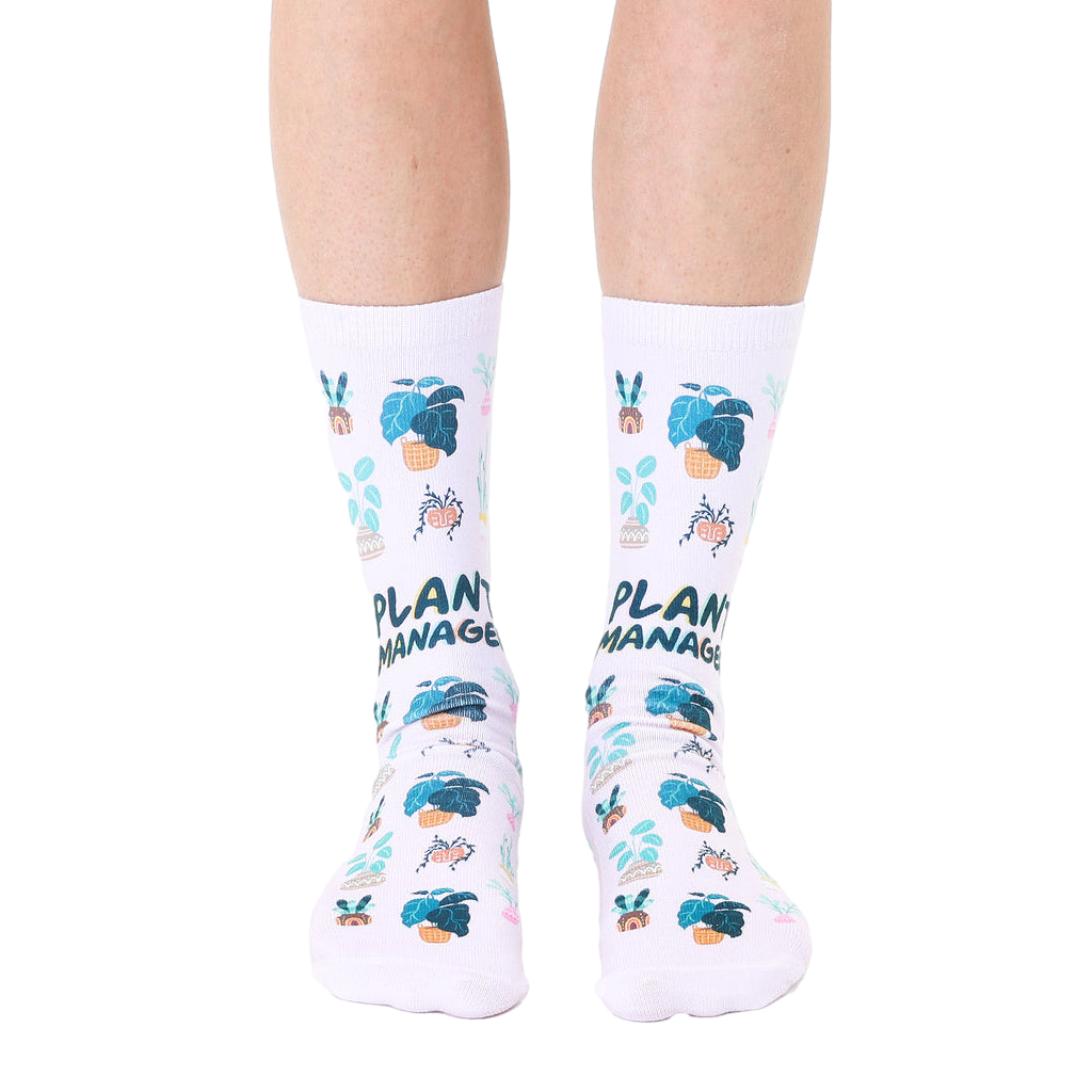 White crew socks with a repeating pattern of potted plants and the text 'Plant Manager' in teal and pink. [lf]
