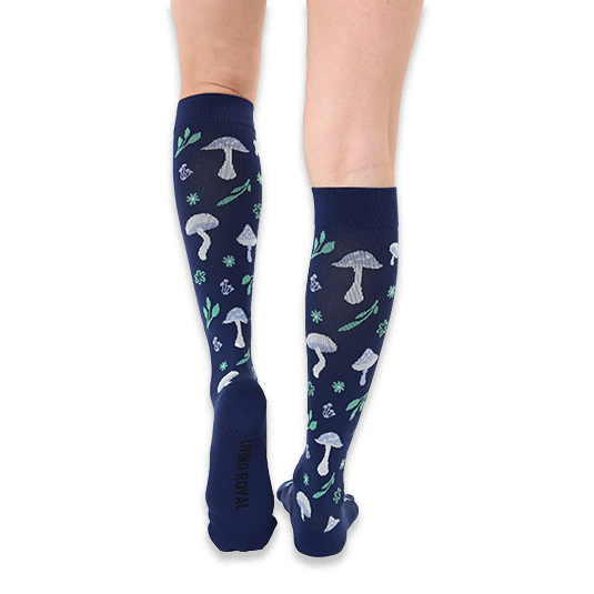 Back view of legs wearing navy blue knee-high socks showing the light blue mushroom and green leaf patterns on the calves.