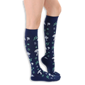 Side profile of a person wearing navy blue knee-high socks patterned with light blue mushrooms and mint green foliage.
