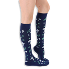 Side profile of a person wearing navy blue knee-high socks patterned with light blue mushrooms and mint green foliage.