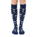 Front view of knee-high dark navy socks featuring a continuous pattern of light blue mushrooms and mint green woodland leaves.