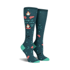 Pair of teal knee-high socks with a 'Drop It Like It's Hot' design. Campfire graphics, flaming hearts, and crossed utensils are featured on a teal background.