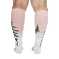 Back view of model wearing pink and white knee-high socks with a winter scene.
