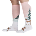 Lifestyle shot of model wearing pink and white knee-high socks with a winter scene.