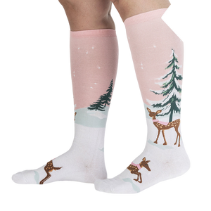 Lifestyle shot of model wearing pink and white knee-high socks with a winter scene.