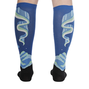 A pair of blue calf-length socks with a black foot and cuff. The socks have an all-over pattern of white and green mountains with a blue sky and white stars.