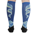 Rear view of the socks on a model's legs, highlighting the symmetrical design and glow-in-the-dark feature.