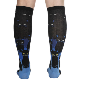 A pair of black knee-high socks with a pattern of yellow cat eyes.