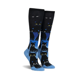 black knee-high womens socks with a grid pattern of yellow-eyed, blue-outlined black cartoon cats. glow in the dark.  