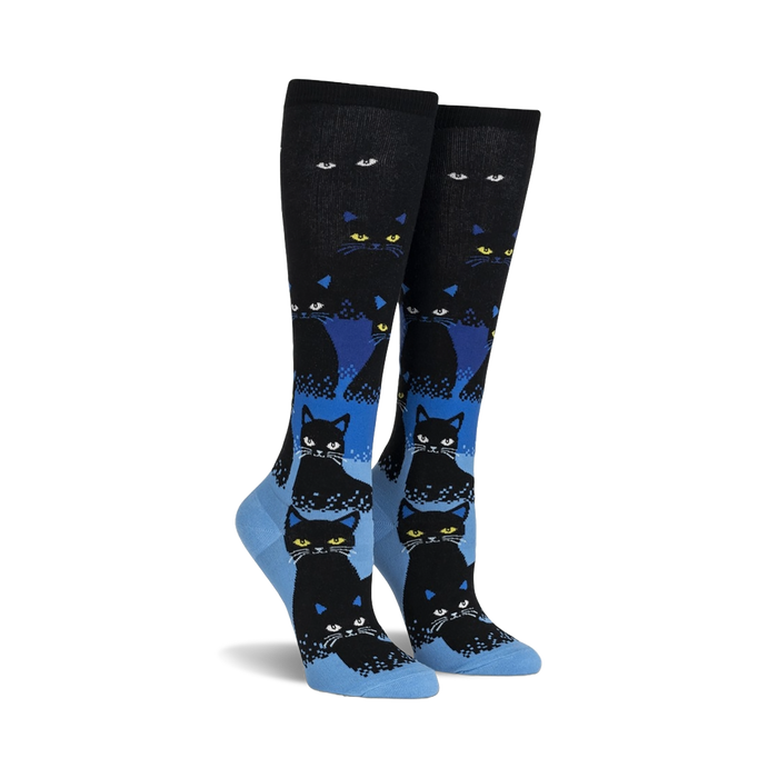 black knee-high womens socks with a grid pattern of yellow-eyed, blue-outlined black cartoon cats. glow in the dark.  