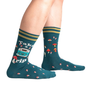A pair of dark green socks with a pattern of red and white mushrooms, blue and white flowers, and a white camper van with the words 