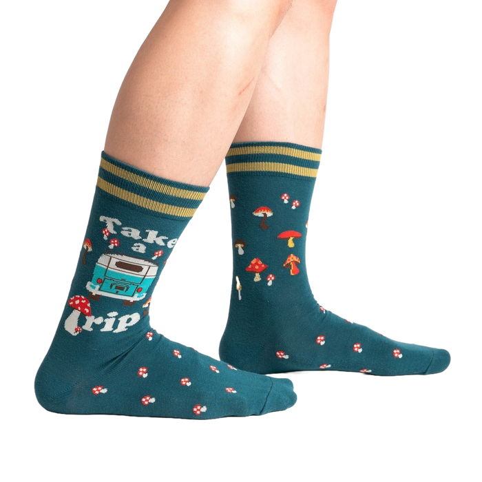 A pair of dark green socks with a pattern of red and white mushrooms, blue and white flowers, and a white camper van with the words 