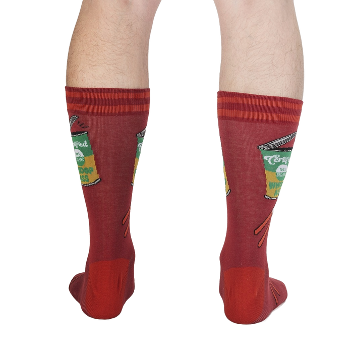A pair of red calf-length socks with a pattern of green and white cans of soup on them.