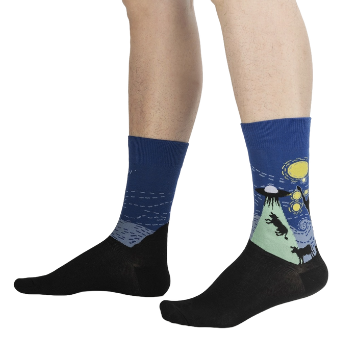 A pair of socks with a dark blue background and a design of black wolves howling at a yellow moon in a starry night sky.