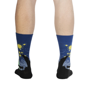 A pair of socks with a dark blue background and a design of black wolves howling at a yellow moon in a starry night sky.
